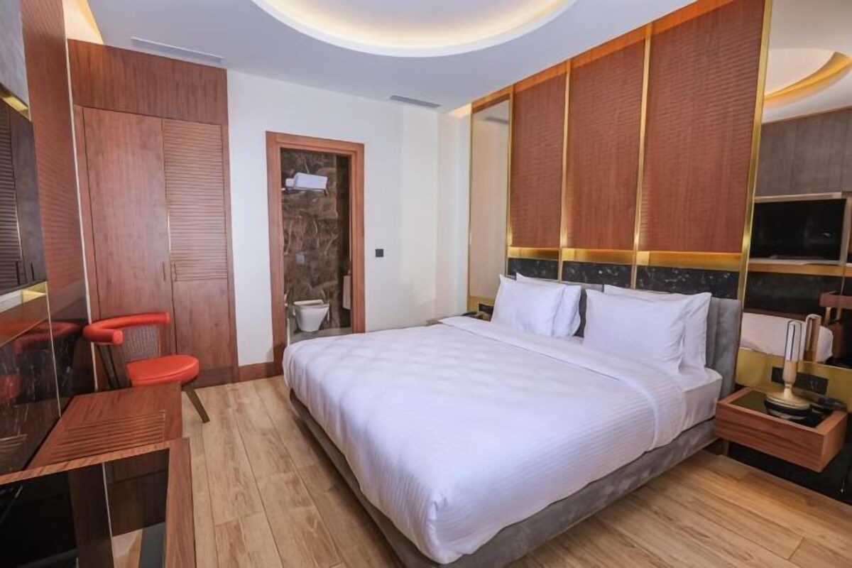 A bedroom with a bed, wooden wardrobe, and a desk.