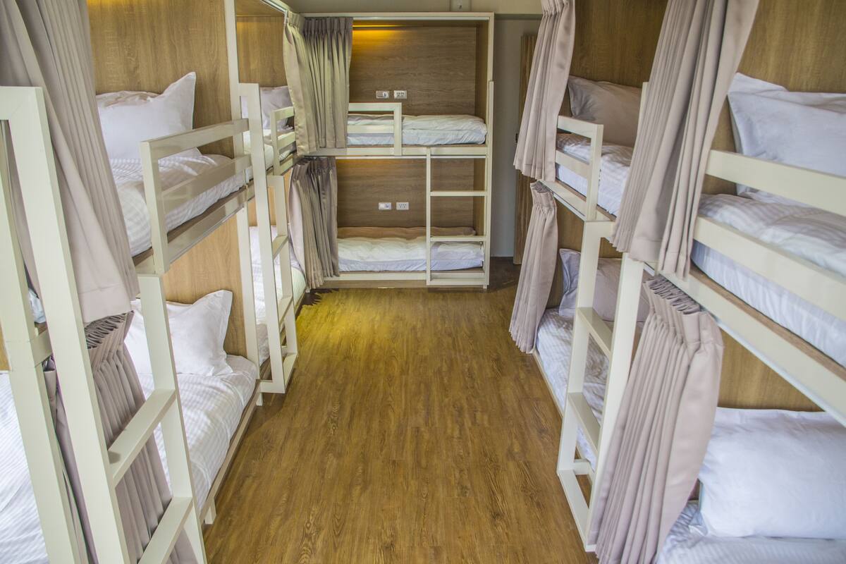 A bunk bed room with wooden floors and white bedding.