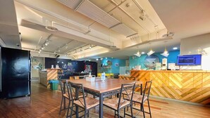 A modern restaurant with a wooden dining area, a counter with a wooden herringboard, and a blue accent wall. - Paper Plane Hostel (Kaohsiung)