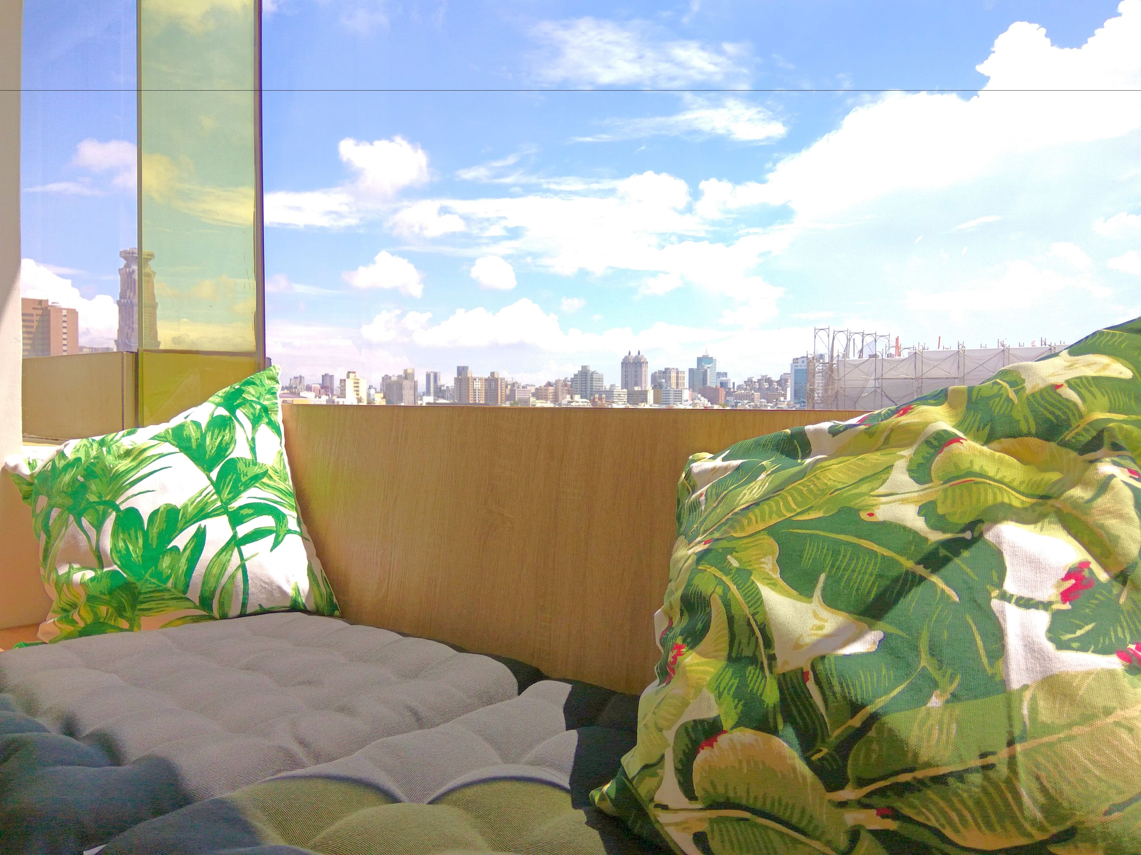 Un dormitorio con vista a la ciudad, una cama con almohadones estampados y un cabecero de madera.