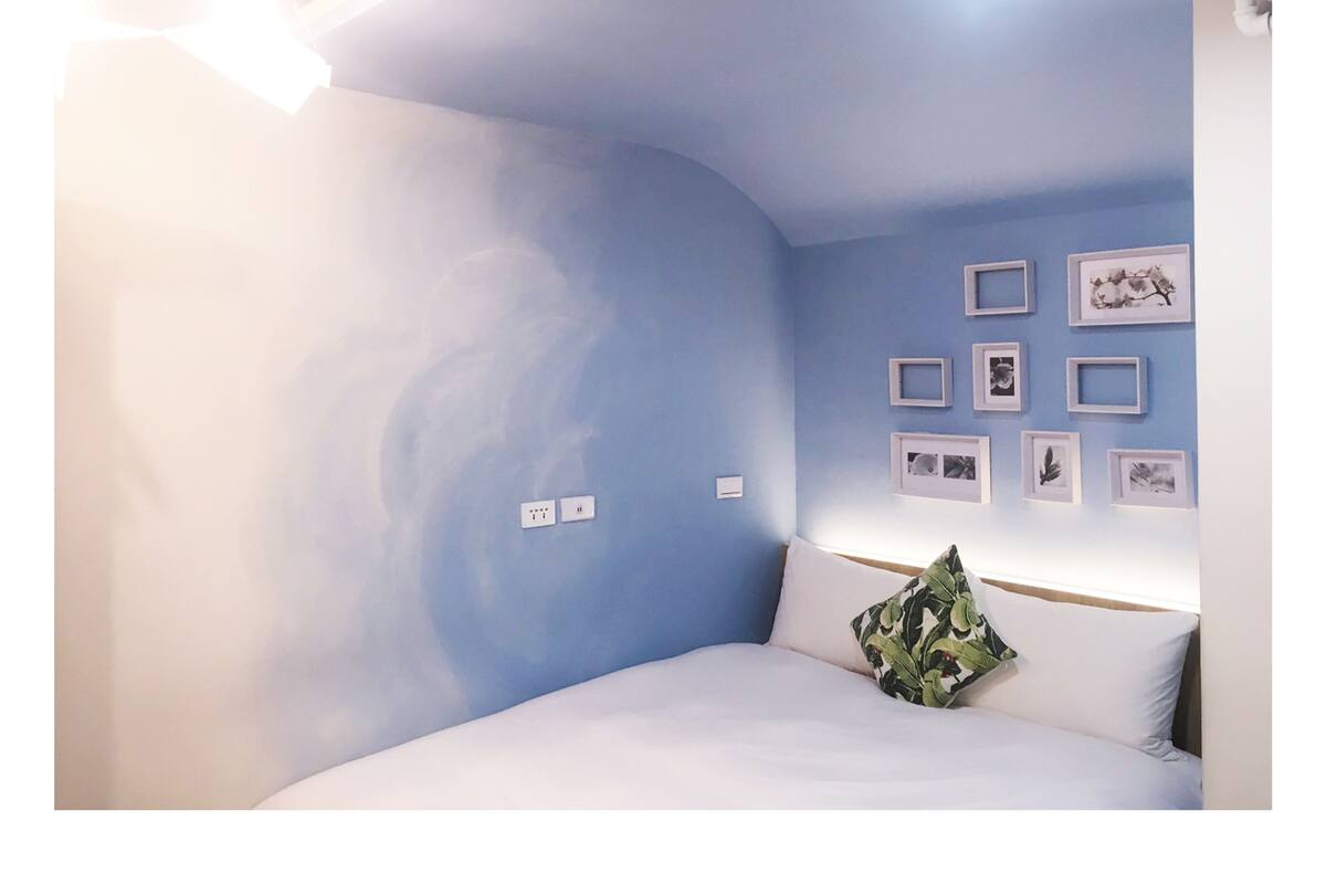 A bedroom with a curved ceiling, a bed with white bedding, and a wall with framed pictures.