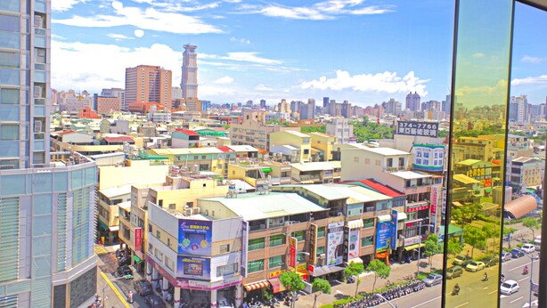 A cityscape with various buildings, including a prominent tower, through a window. - Paper Plane Hostel (Kaohsiung)