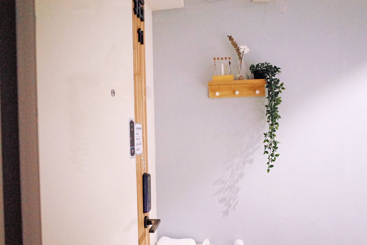 A bathroom with a wooden shelf holding a plant, a towel, and toiletries.