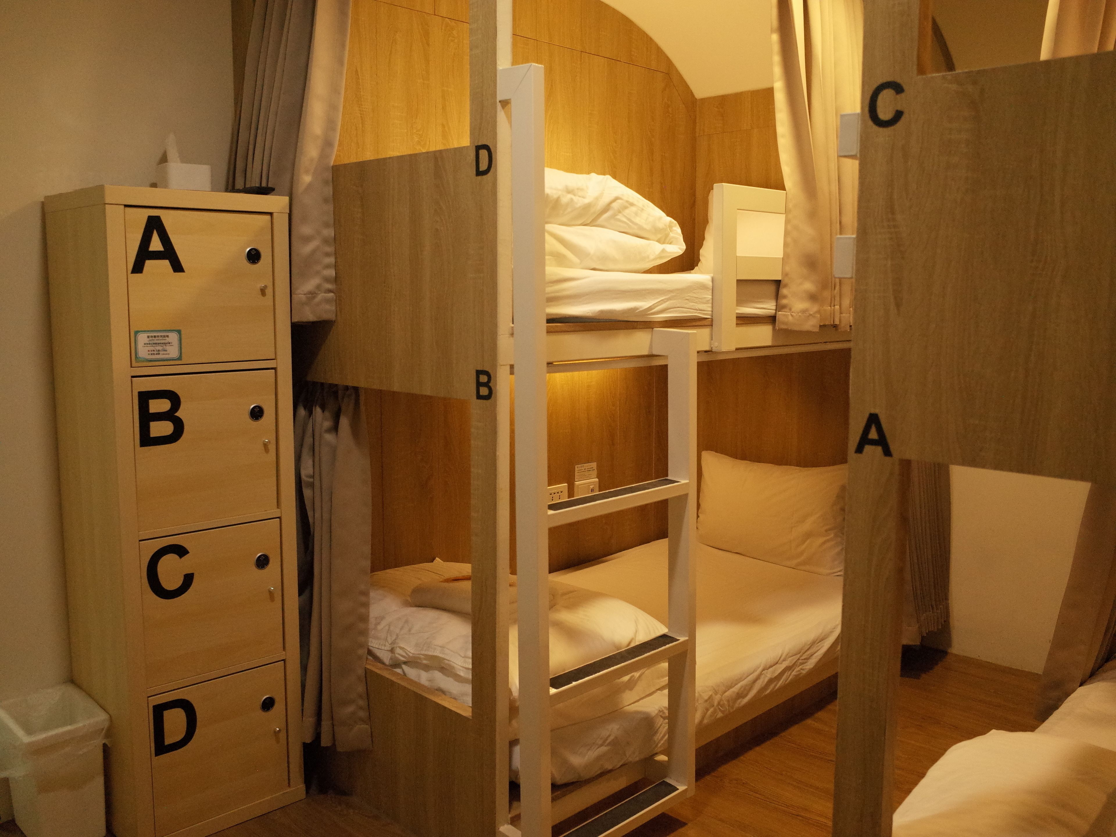 Een slaapkamer met een stapelbed en een houten garderobe met de letters A, B, C en D.