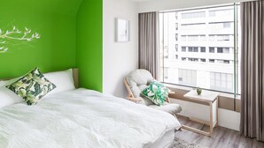 A modern hotel room with a large bed, a green accent wall, a window with curtains, and a view of a building outside. - Paper Plane Hostel (Kaohsiung)