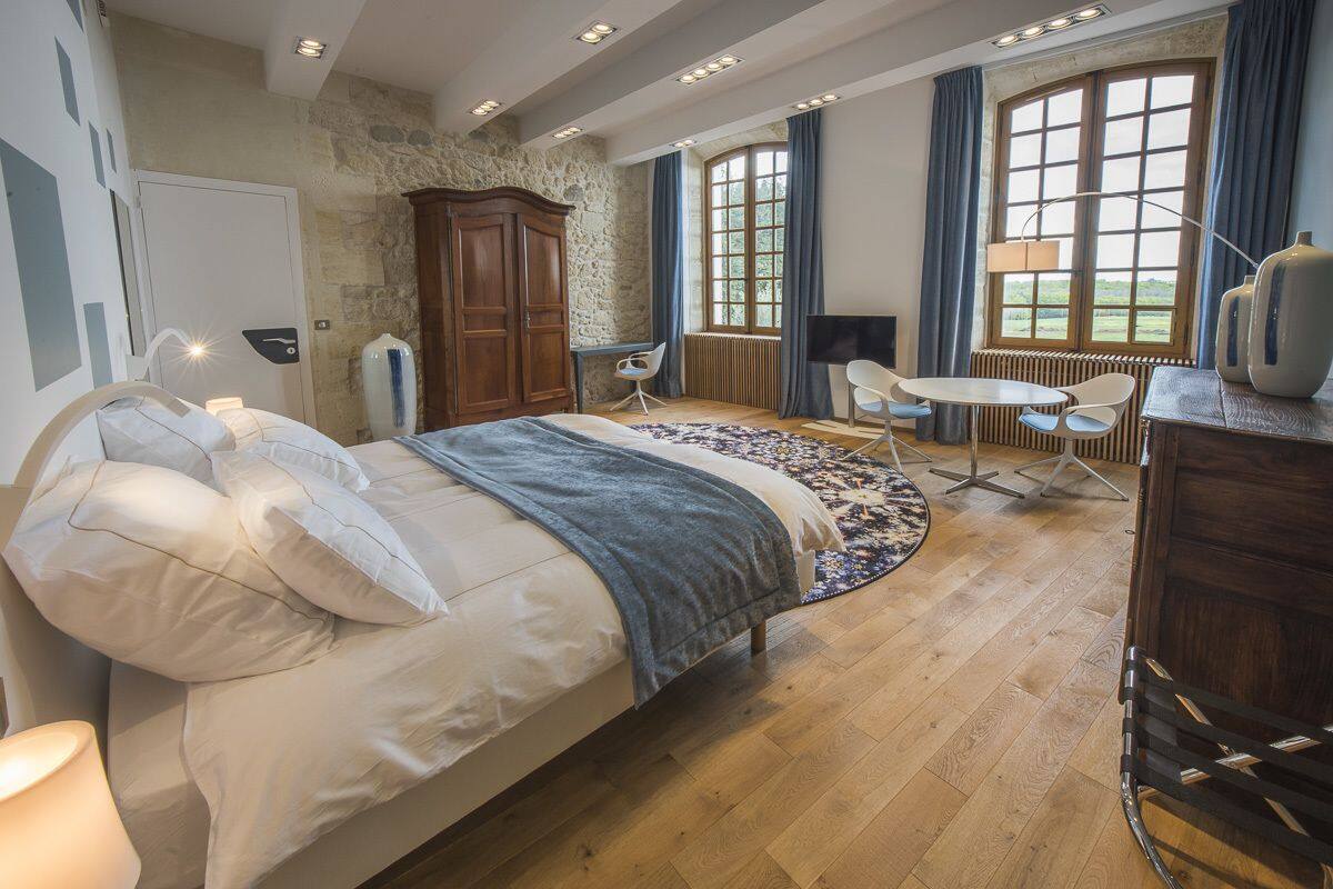 Une chambre à coucher avec un grand lit, un bureau, une chaise, une petite table et un fauteuil de massage.
