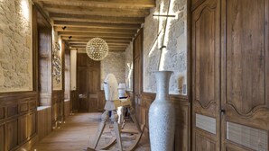 A hallway with wooden paneling, a large white vase, and a wooden rocking horse. - Château Prieuré Marquet - Chambres d'Hôtes D'exception (Saint-Martin-du-Bois)