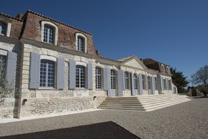 A historic building with a stone facade, multiple windows with shutters, and a set of stairs leading to the entrance. - Château Prieuré Marquet - Chambres d'Hôtes D'exception (Saint-Martin-du-Bois)