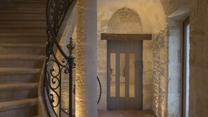 A stone staircase with a wrought iron railing leading to a door with vertical blinds. - Château Prieuré Marquet - Chambres d'Hôtes D'exception (Saint-Martin-du-Bois)