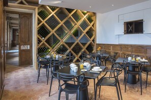 A restaurant with a modern interior, featuring a wine cellar wall, multiple tables and chairs, and a stone floor. - Château Prieuré Marquet - Chambres d'Hôtes D'exception (Saint-Martin-du-Bois)