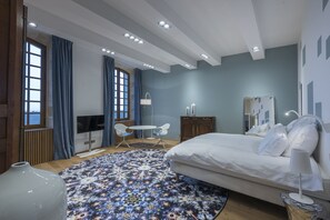 A modern bedroom with a large bed, a desk, and a TV. - Château Prieuré Marquet - Chambres d'Hôtes D'exception (Saint-Martin-du-Bois)