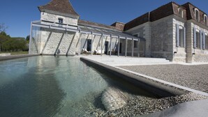 A historic building with a swimming pool, stone walls, and a glass-enclosed structure. - Château Prieuré Marquet - Chambres d'Hôtes D'exception (Saint-Martin-du-Bois)