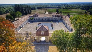 An aerial view of a historic building with a courtyard, surrounded by vineyards and trees. - Château Prieuré Marquet - Chambres d'Hôtes D'exception (Saint-Martin-du-Bois)