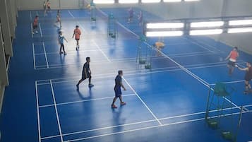 Eine Sporthalle mit Badmintonplätzen, auf denen mehrere Spieler und Zuschauer sind.
