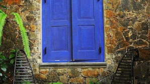 A stone wall with a blue door and two metal benches. - Boulder Garden Hotel (Kalawana)