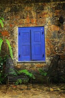 A stone wall with a blue door and two metal benches.