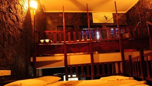 A bunk bed room with a stone wall and a painting of a bird on the wall. - Boulder Garden Hotel (Kalawana)