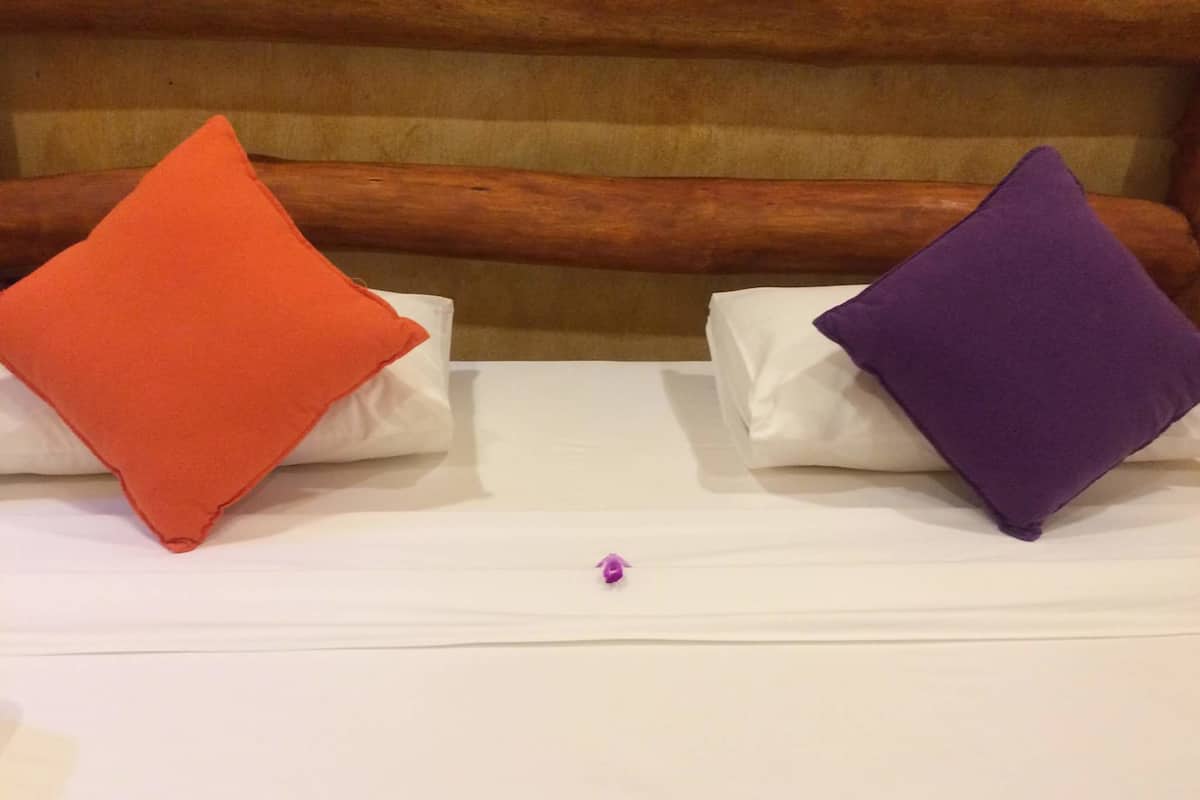 A bed with two pillows, one orange and one purple, and a wooden headboard.