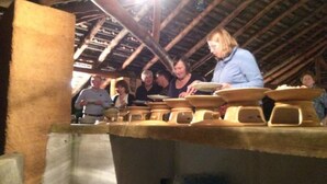 Een groep mensen in een rustieke keuken met houten balken en keramiek.