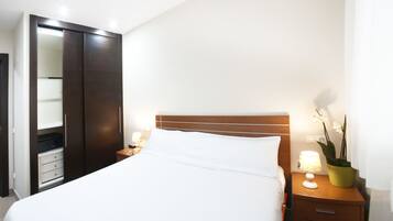 A hotel room with a bed, nightstands, a wardrobe, and a potted plant.