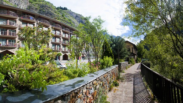 Un hôtel à plusieurs étages, doté de balcons, d’une façade en pierre et surplombant un paysage montagneux.