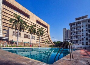 A swimming pool with a modern building in the background. - YMCA Tourist Hostel (New Delhi)