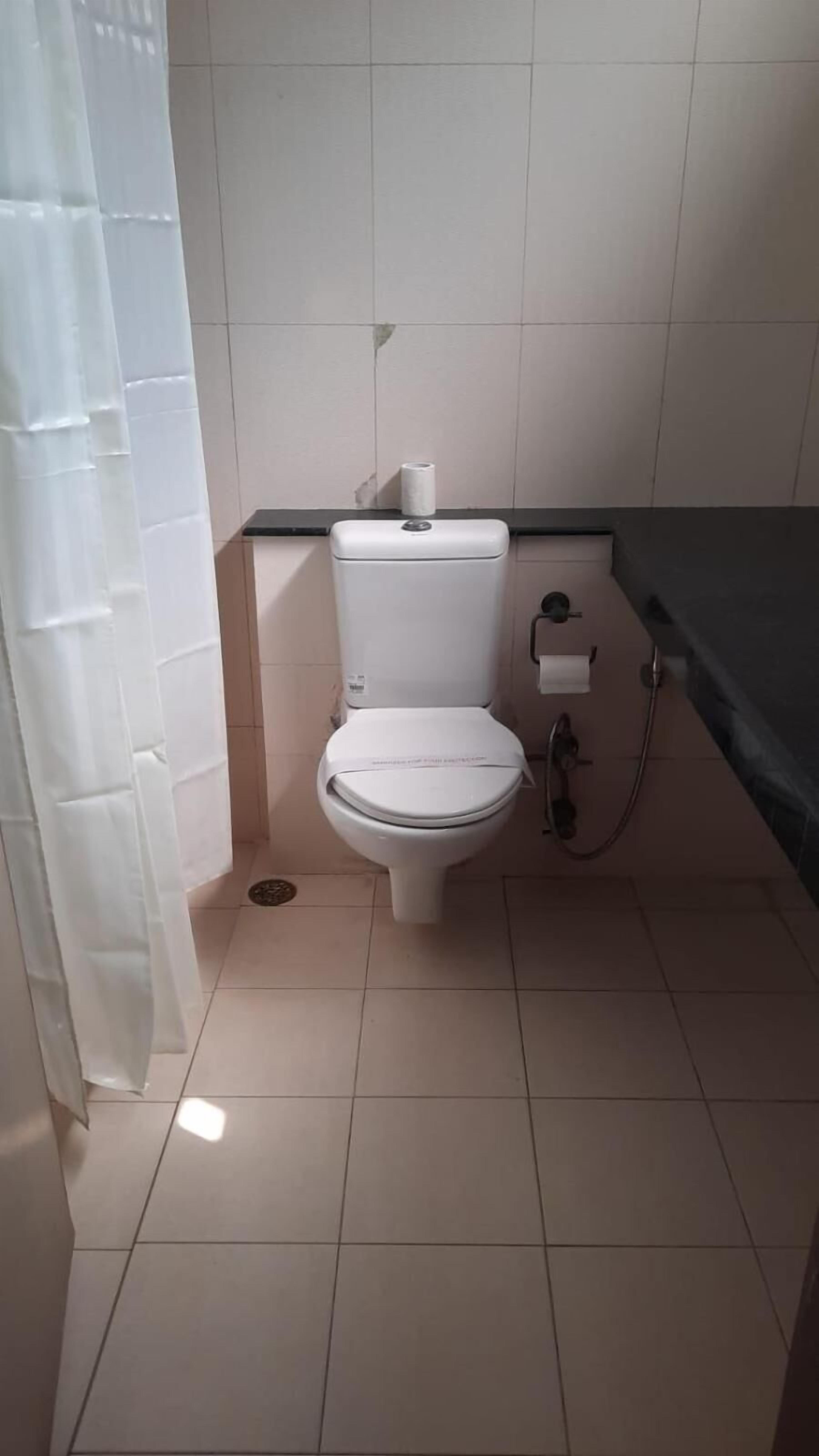 A standard bathroom with a toilet, a towel rack, and a shower area.
