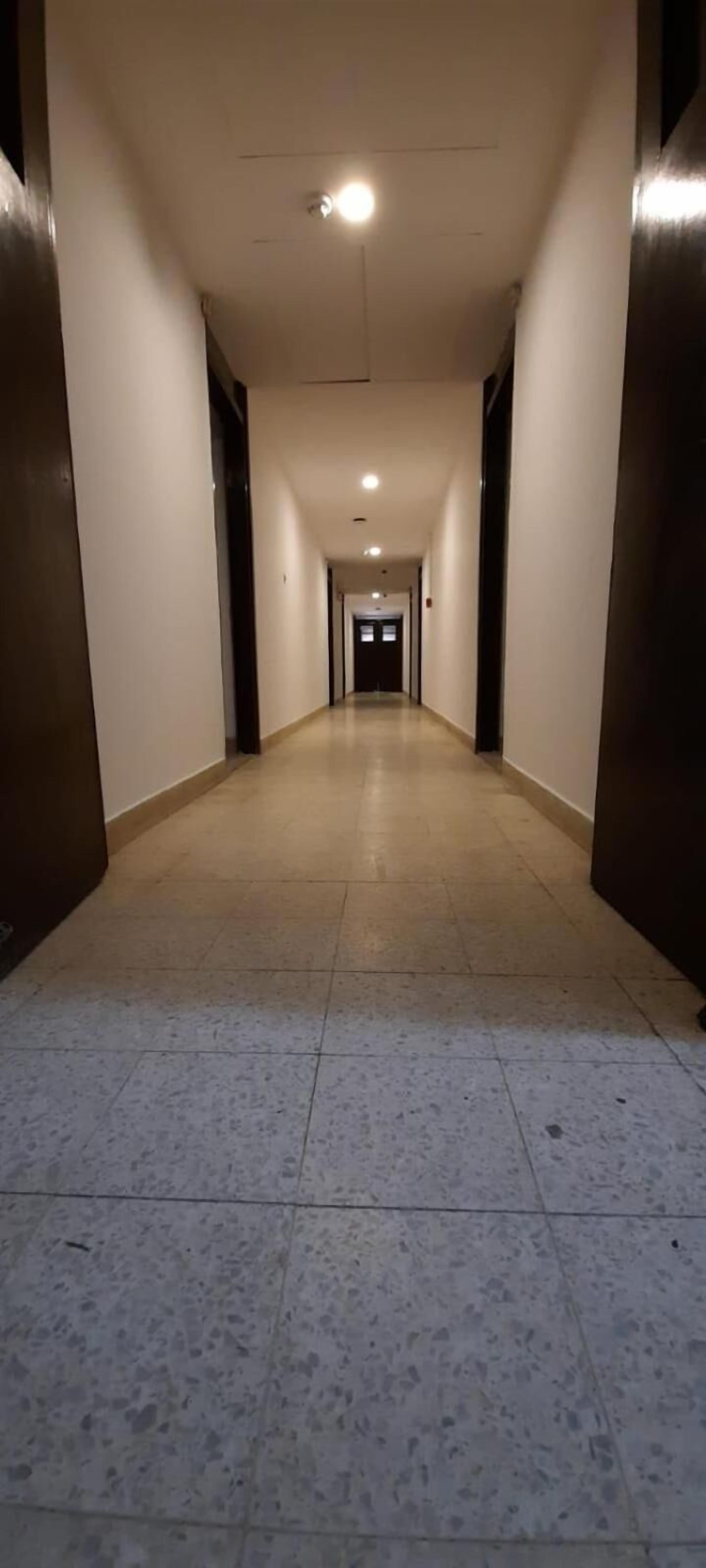 A long, narrow hallway with a tiled floor and white walls.