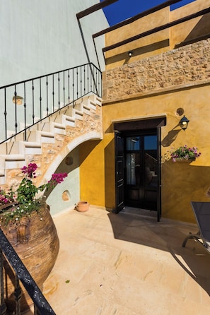 A stone staircase leading to a door, a potted plant, and a wall-mounted light fixture.