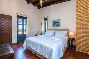 A bedroom with a bed, a wooden bench, a door, and a wall with a brick pattern.