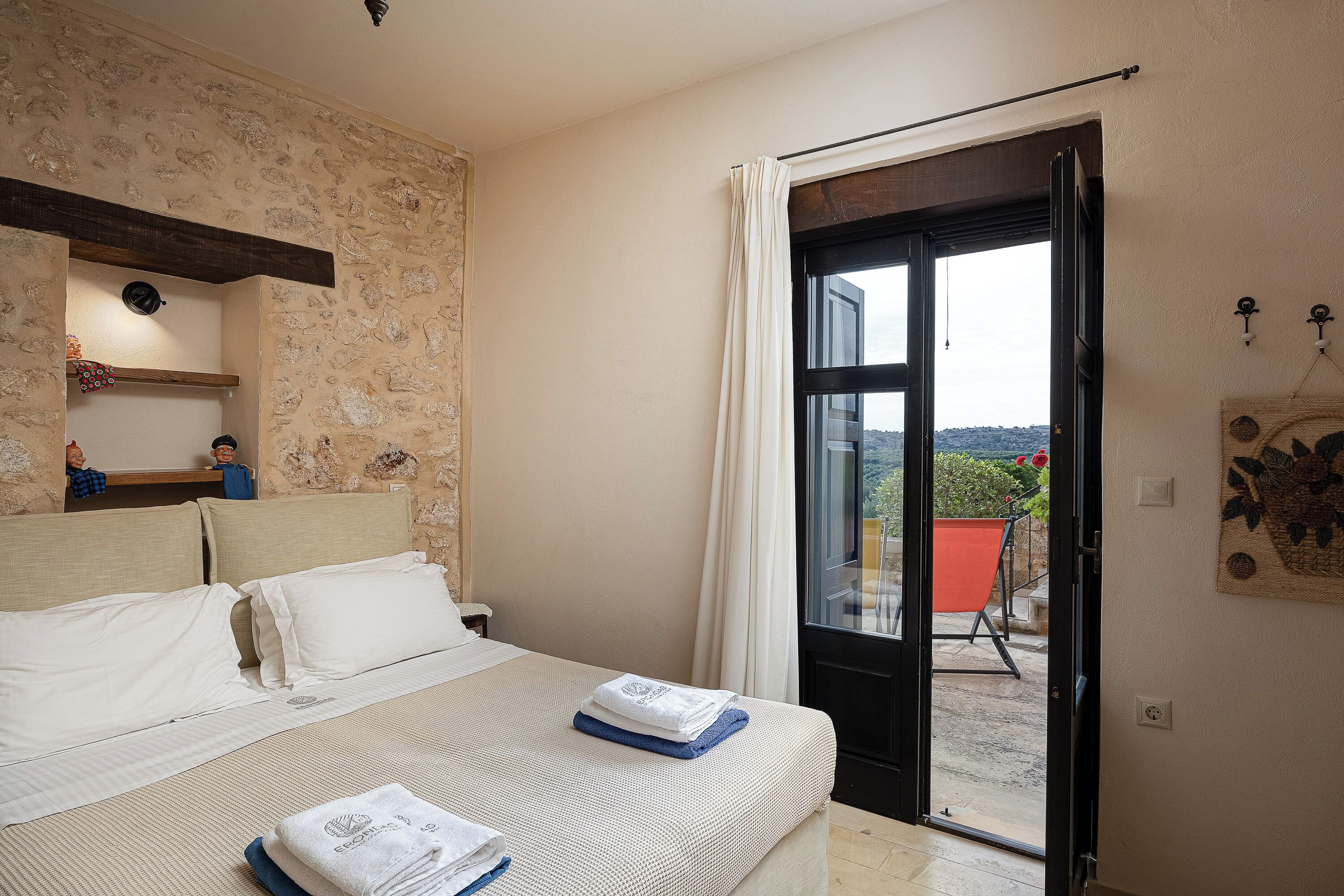 Ein Schlafzimmer mit Bett, Fenster, Tür und Blick ins Freie.