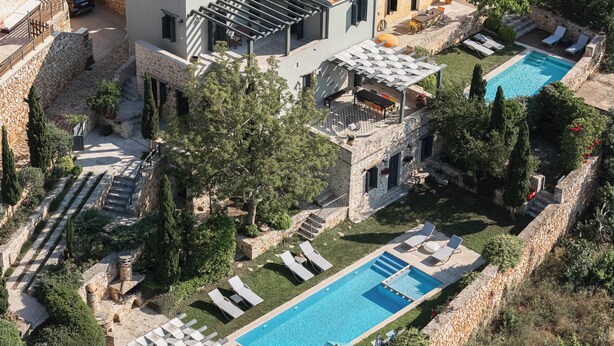 Un espace piscine aménagé avec des chaises longues, une pergola et un mur en pierre.