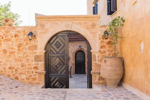 A stone archway leading to a building with a large potted plant beside it. - Erondas Cretan Country Villas (Mylopotamos)