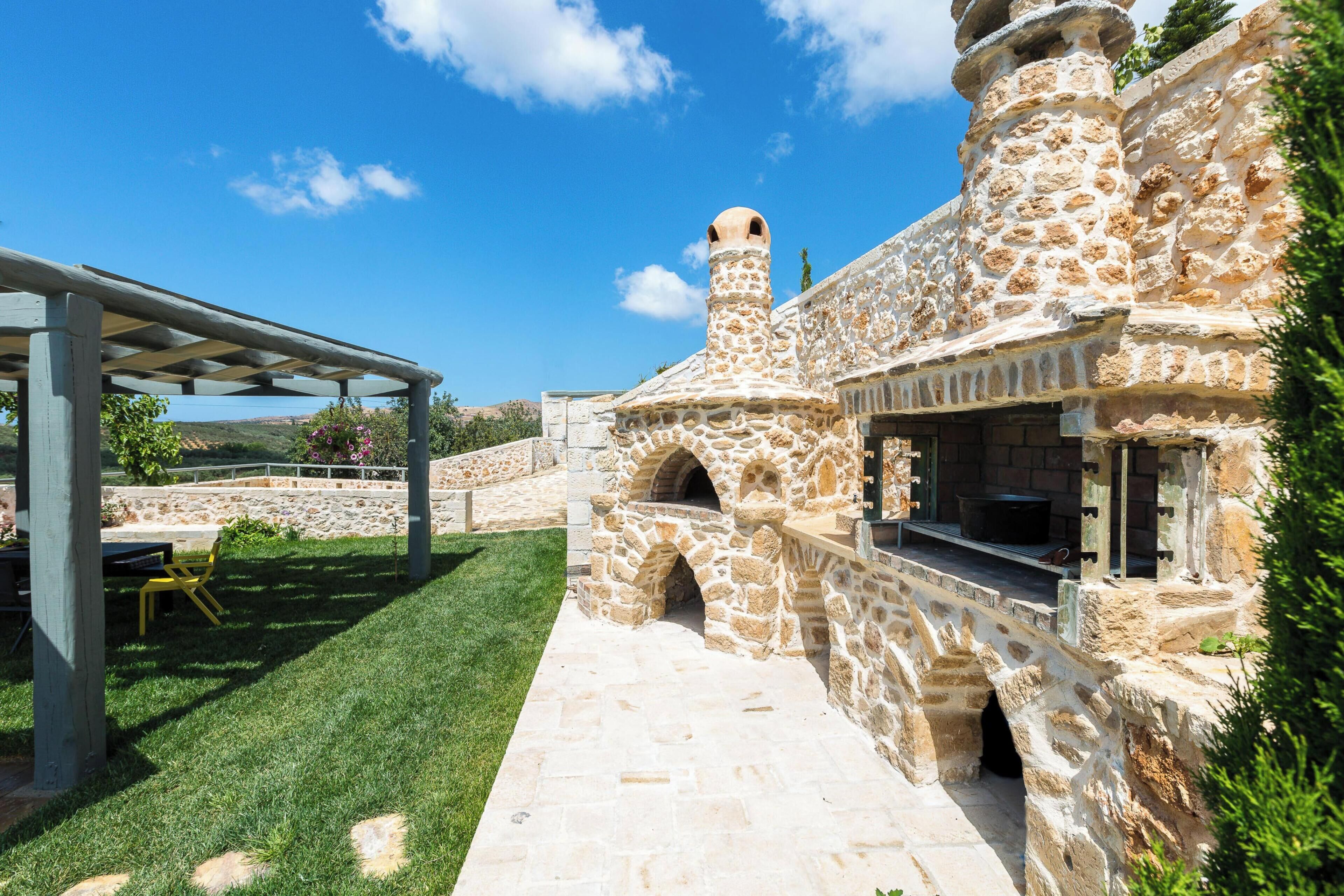 Un edificio de piedra con chimenea, un porche cubierto y un sendero de piedra.