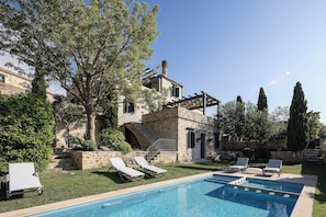 A pool with lounge chairs, a stone building, and a tree. - Erondas Cretan Country Villas (Mylopotamos)