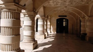 A corridor with classical columns and an arched ceiling with detailed carvings. - Hotel de l'Ocean (La Rochelle)