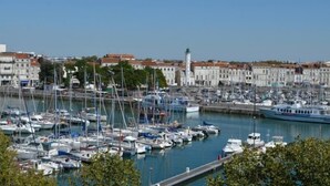 A marina with numerous boats docked, surrounded by buildings with red-tiled roofs. - Hotel de l'Ocean (La Rochelle)