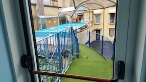 A view of a swimming pool with a blue fence and a small grassy area in front. - Hotel San Marco BB (Darfo Boario Terme)