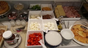 Un buffet proposant une variété de plats, notamment des fromages, des viandes et des condiments.
