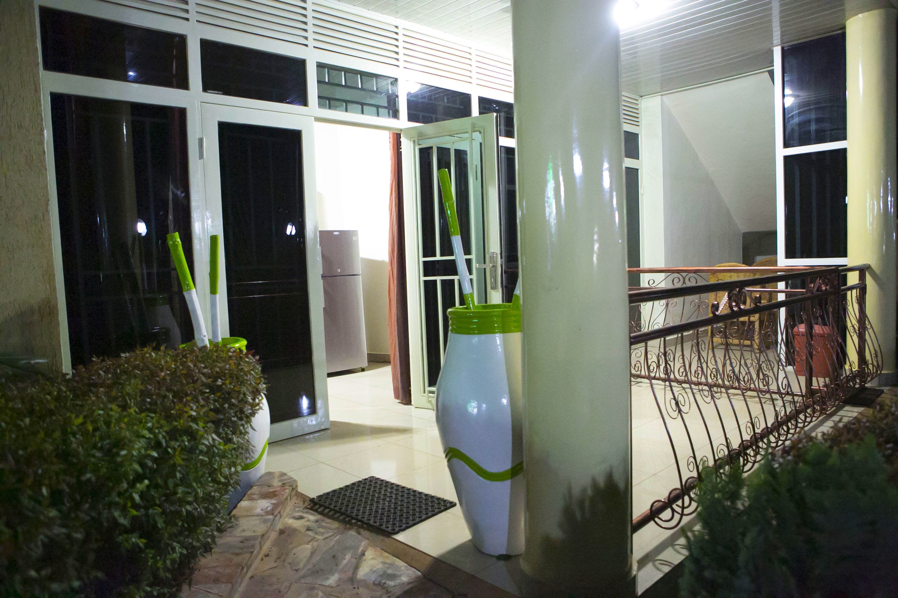 A hotel entrance with a large white vase, a metal railing, and a door leading to the interior.