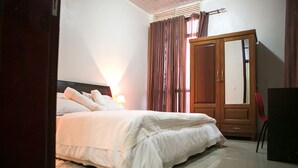 Una cama bien hecha con sábanas blancas en una habitación con un armario de madera y un espejo.