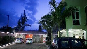 Un edificio con camino de entrada pavimentado, una cabina telefónica roja y coches aparcados.