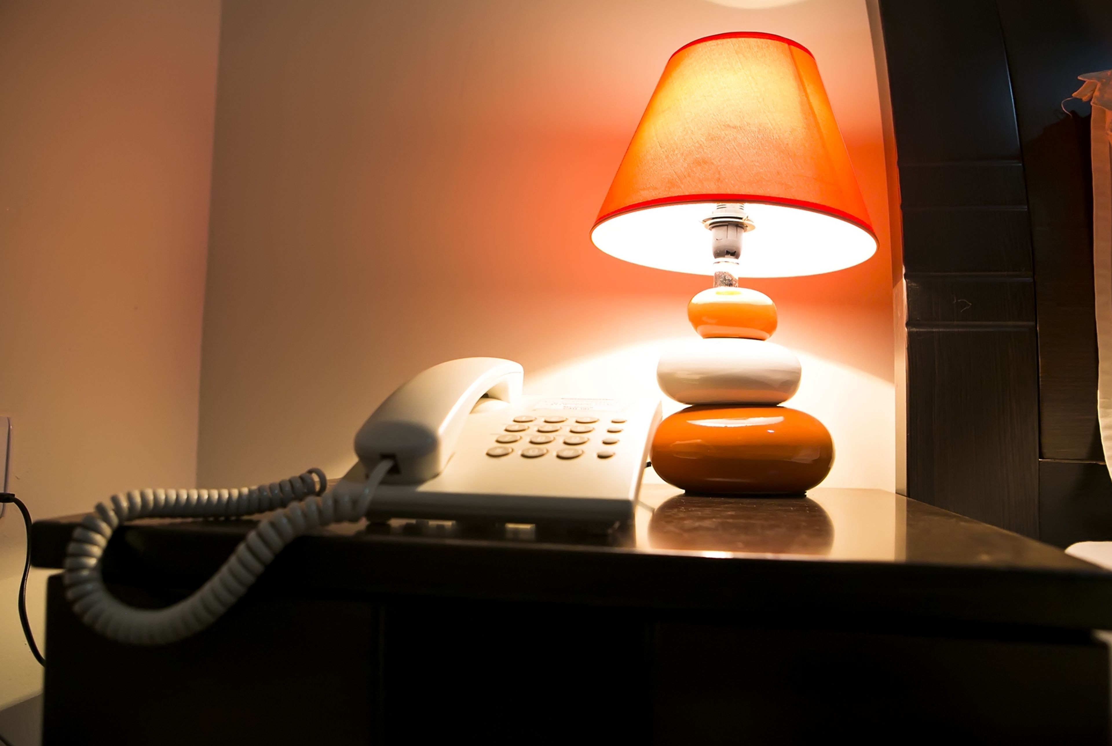 A telephone with a lamp on a desk.