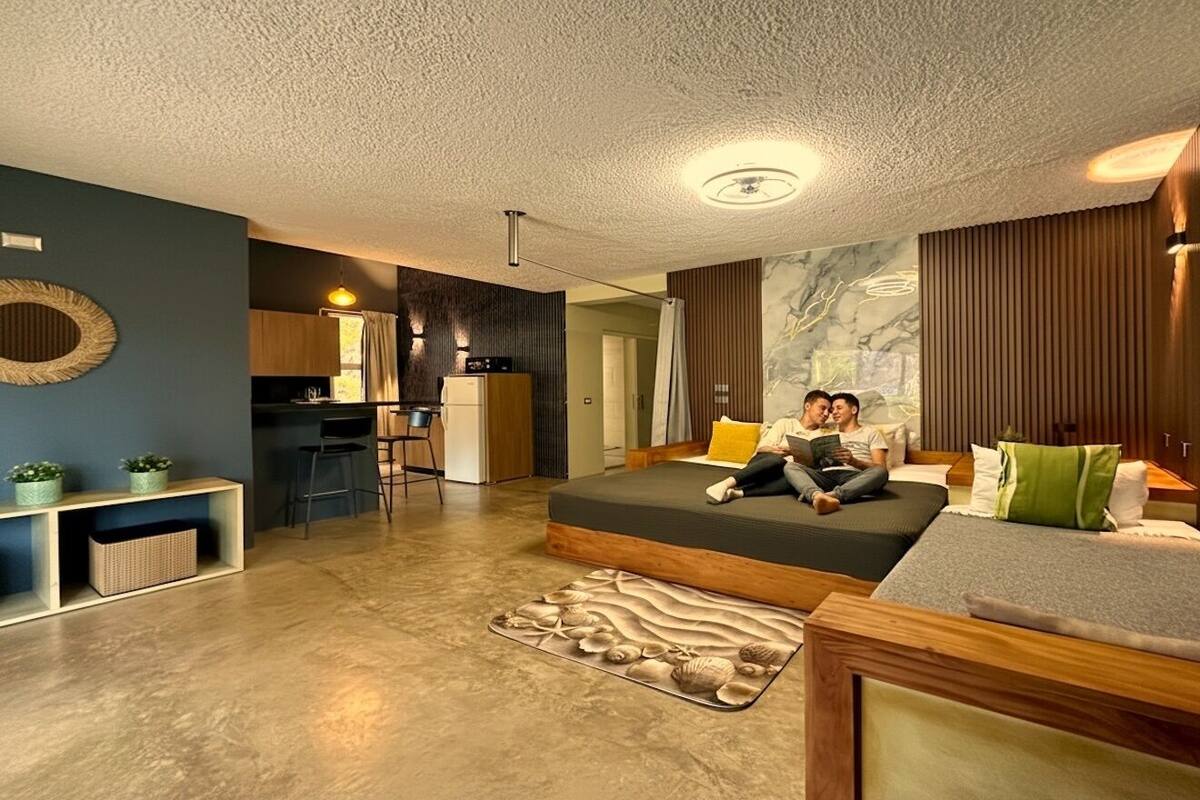 A modern living room with a sofa, a dining area, and a kitchen.