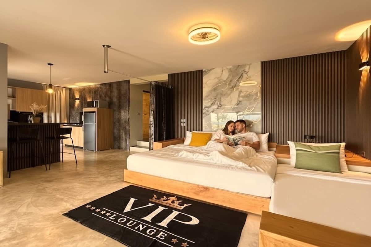 A modern hotel room with a large bed, a desk, and a seating area.