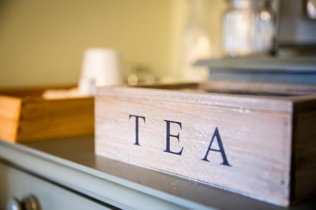 A wooden box labeled 'TEA' on a counter.