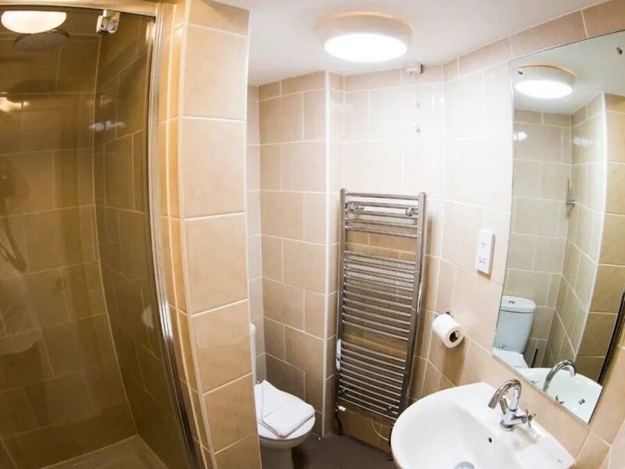 A bathroom with a glass shower enclosure, a toilet, a sink, and a towel rack.
