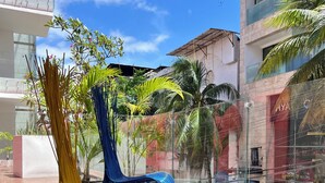 Un espace extérieur moderne, aménagé avec des chaises en osier, une rambarde en verre et offrant une vue sur le paysage urbain.