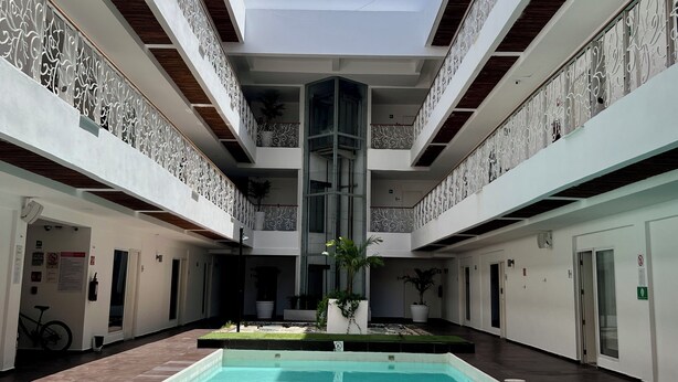 Une piscine dotée d’une colonne centrale, de murs blancs et de balcons agrémentés de rampes décoratives.