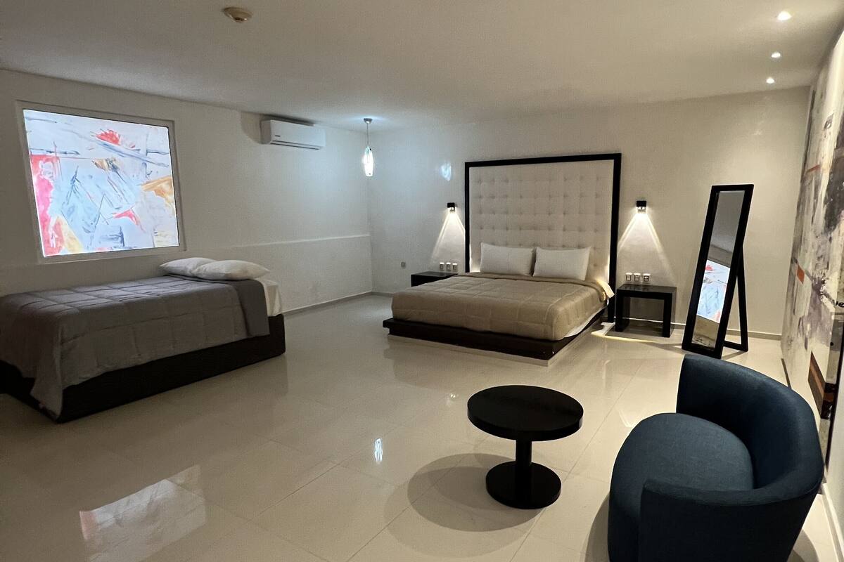 Une chambre d’hôtel avec un lit, un petit lit, une chaise, une table et une grande fenêtre avec une carte.